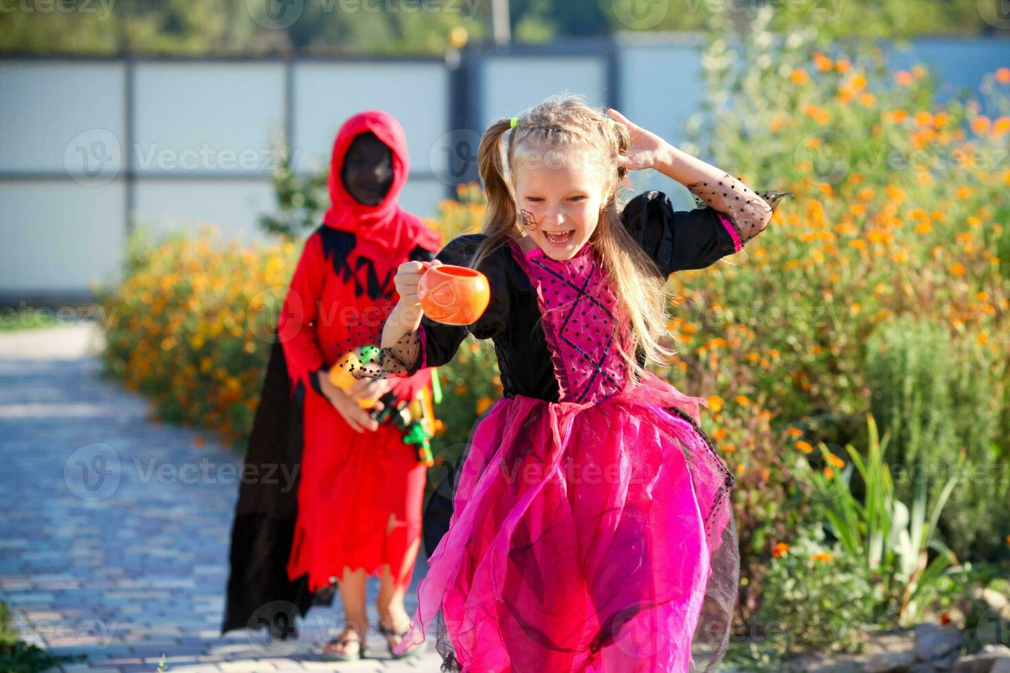 en flicka klädd som en häxa kör bort från en pojke klädd som ett bödel. foto