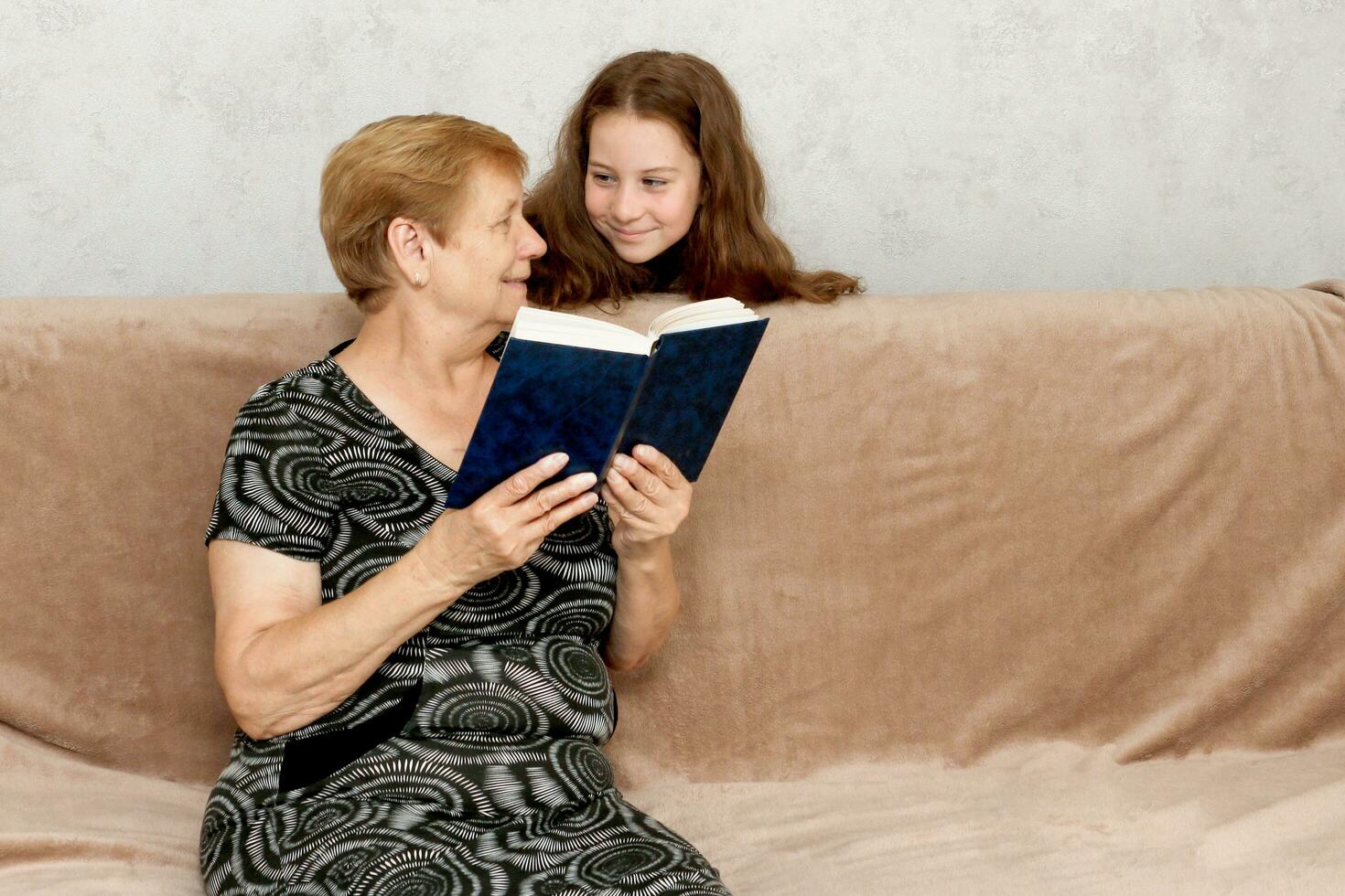 mormor läsning en bok till henne barnbarn foto