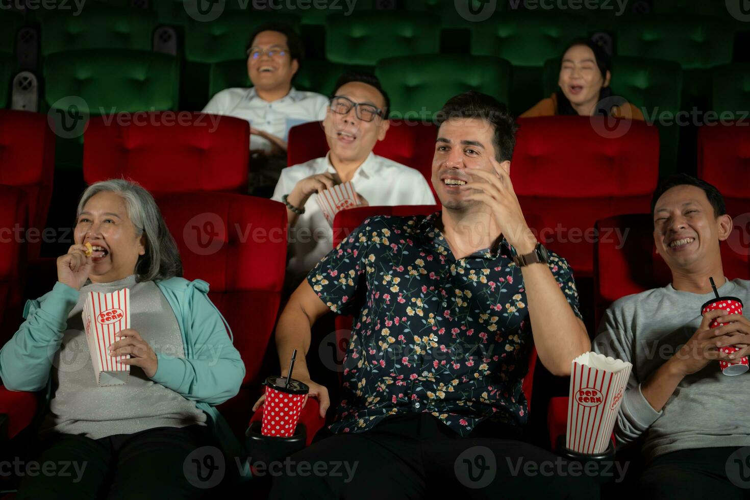 grupp av asiatisk senior vänner tittar på komedi film och skratt på de bio med popcorn foto