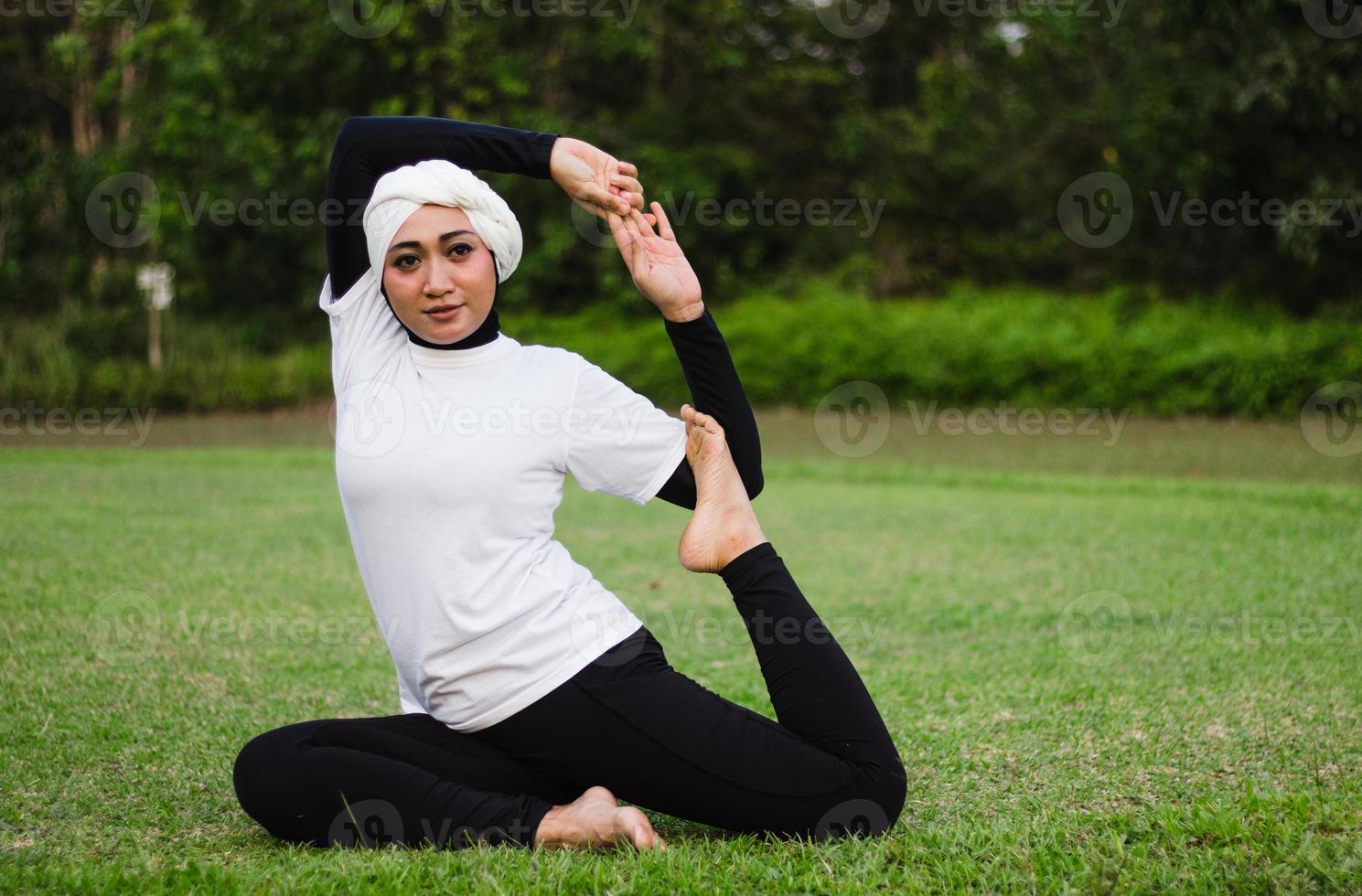 trevlig kvinna i hijab och sportkläder som gör yoga och stretching. foto