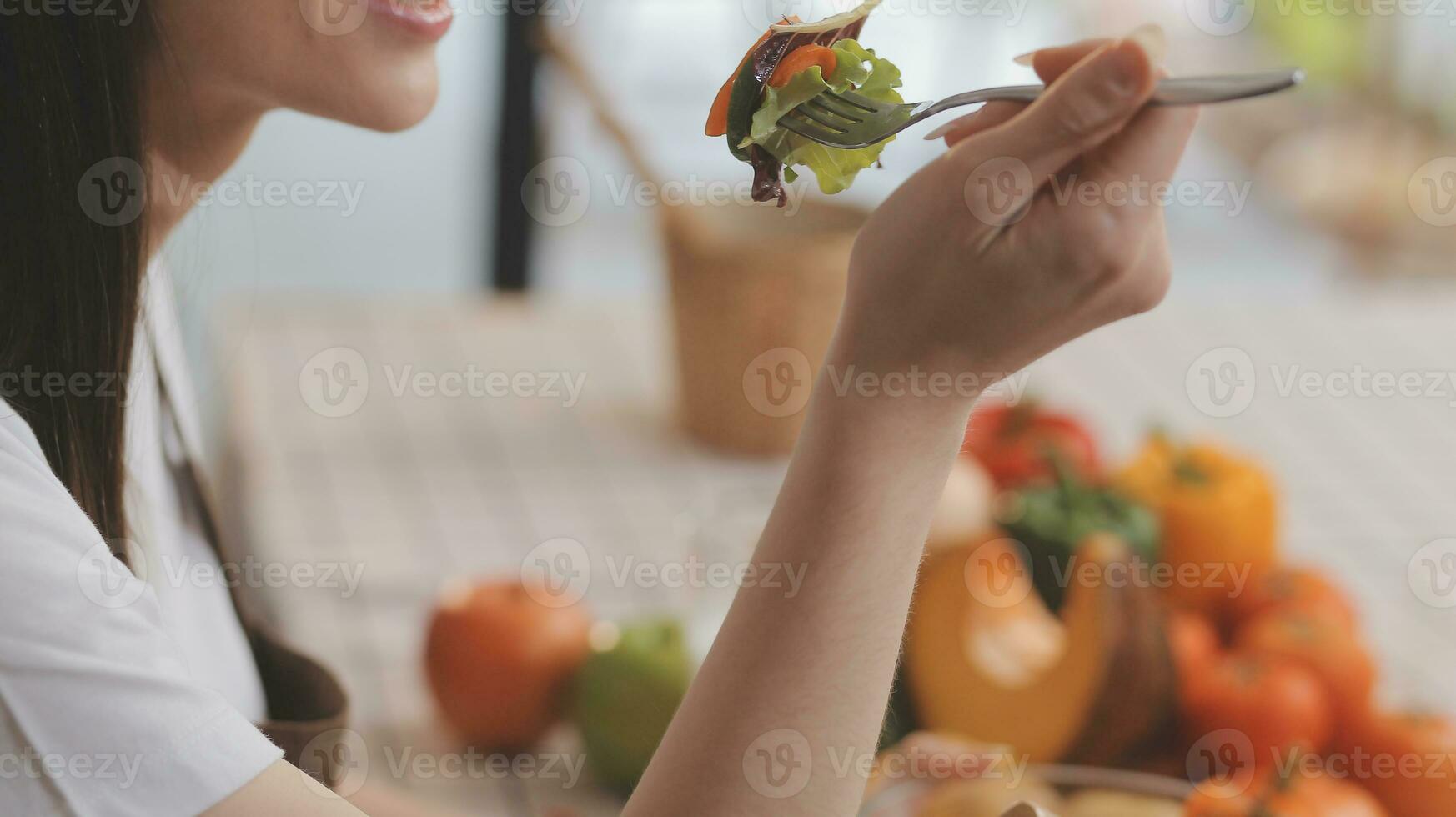 utsökt frukt och grönsaker på en tabell och kvinna matlagning. hemmafru är skärande grön gurkor på en trä- styrelse för framställning färsk sallad i de kök. foto
