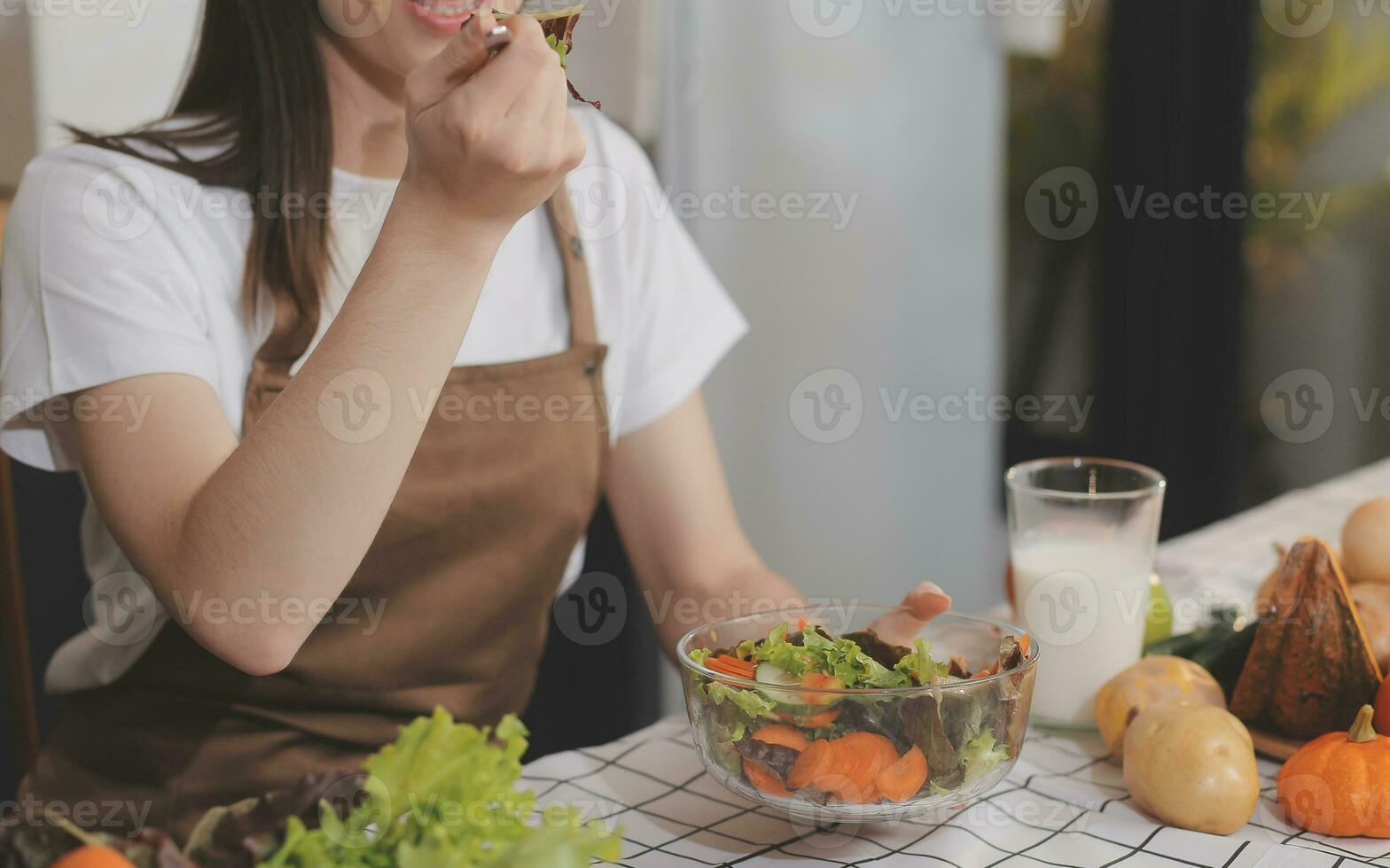 utsökt frukt och grönsaker på en tabell och kvinna matlagning. hemmafru är skärande grön gurkor på en trä- styrelse för framställning färsk sallad i de kök. foto