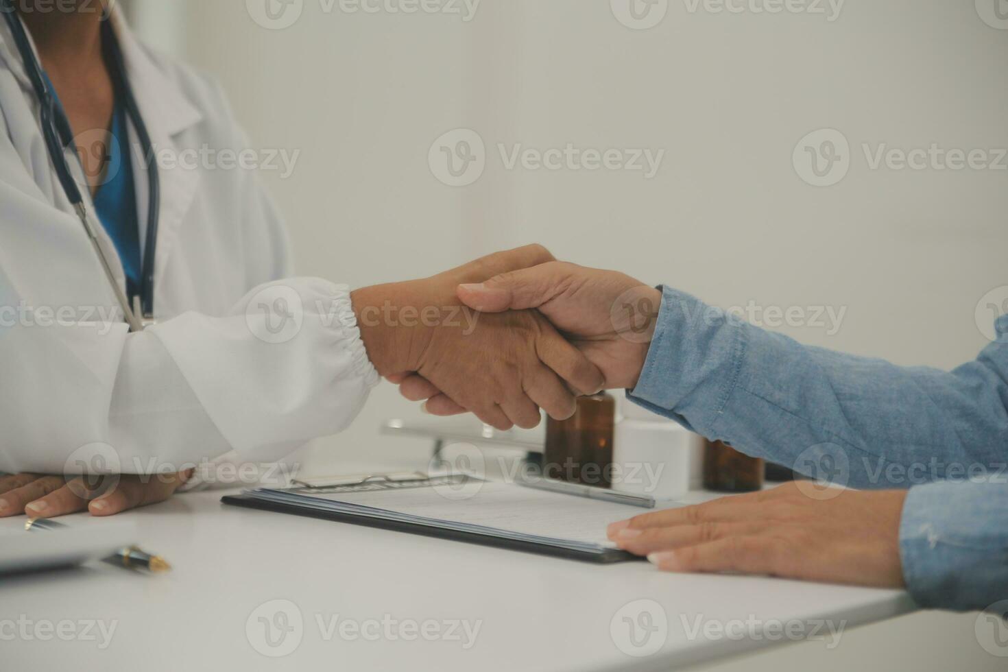leende ung kvinna läkare skaka hand stänga hälsa försäkring handla med äldre patient på samråd i sjukhus. Lycklig kvinna gp handslag hälsning skaffa sig bekant med mogna man i klinik. foto