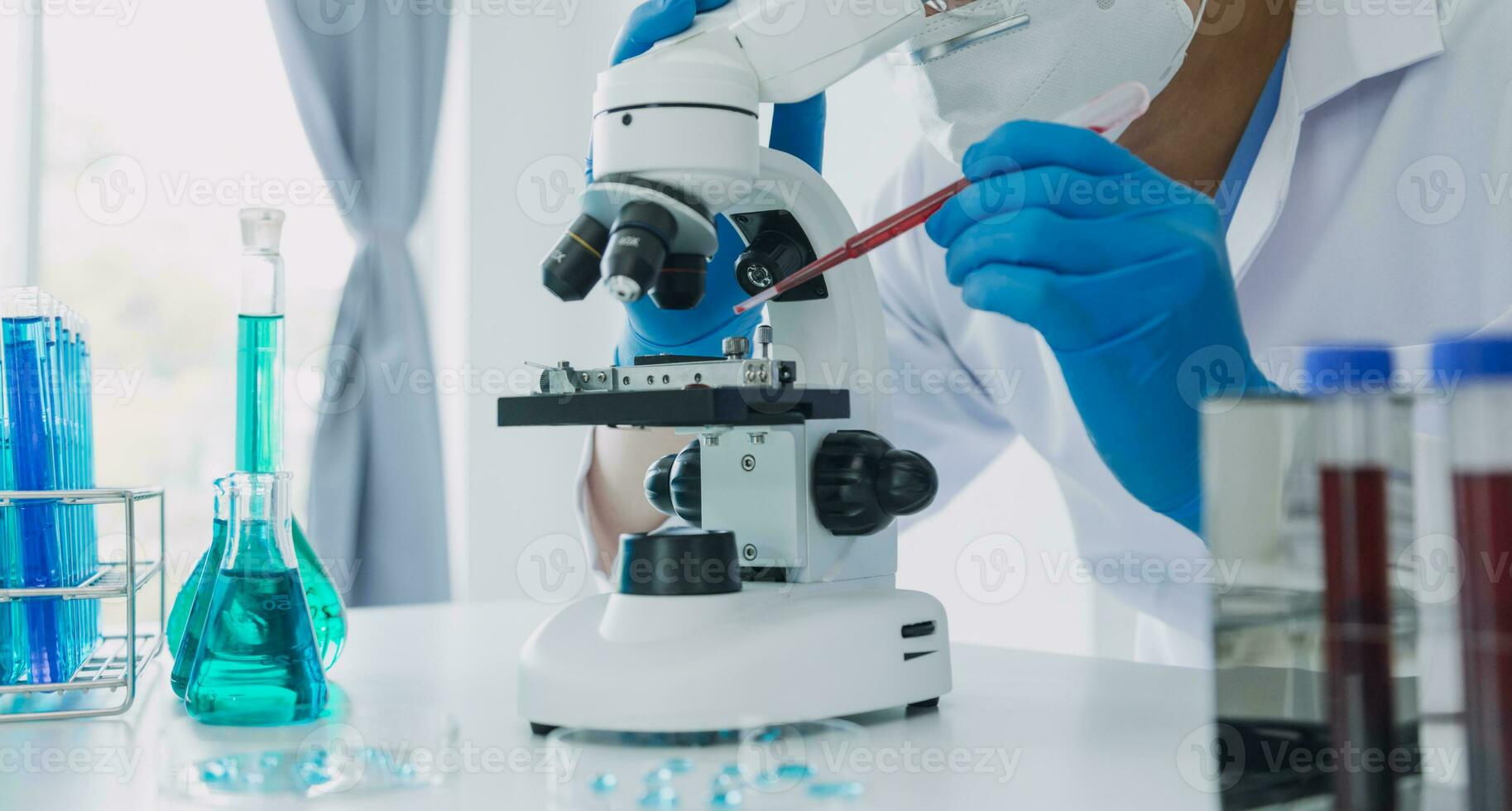 ung vetenskapsmän ledande forskning utredningar i en medicinsk laboratorium, en forskare i de förgrund är använder sig av en mikroskop foto