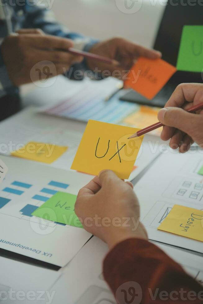 stänga upp ux utvecklare och ui designer brainstorming handla om mobil app gränssnitt trådmodell design på tabell med kund kortfattat och Färg koda på modern office.creative digital utveckling byrå foto