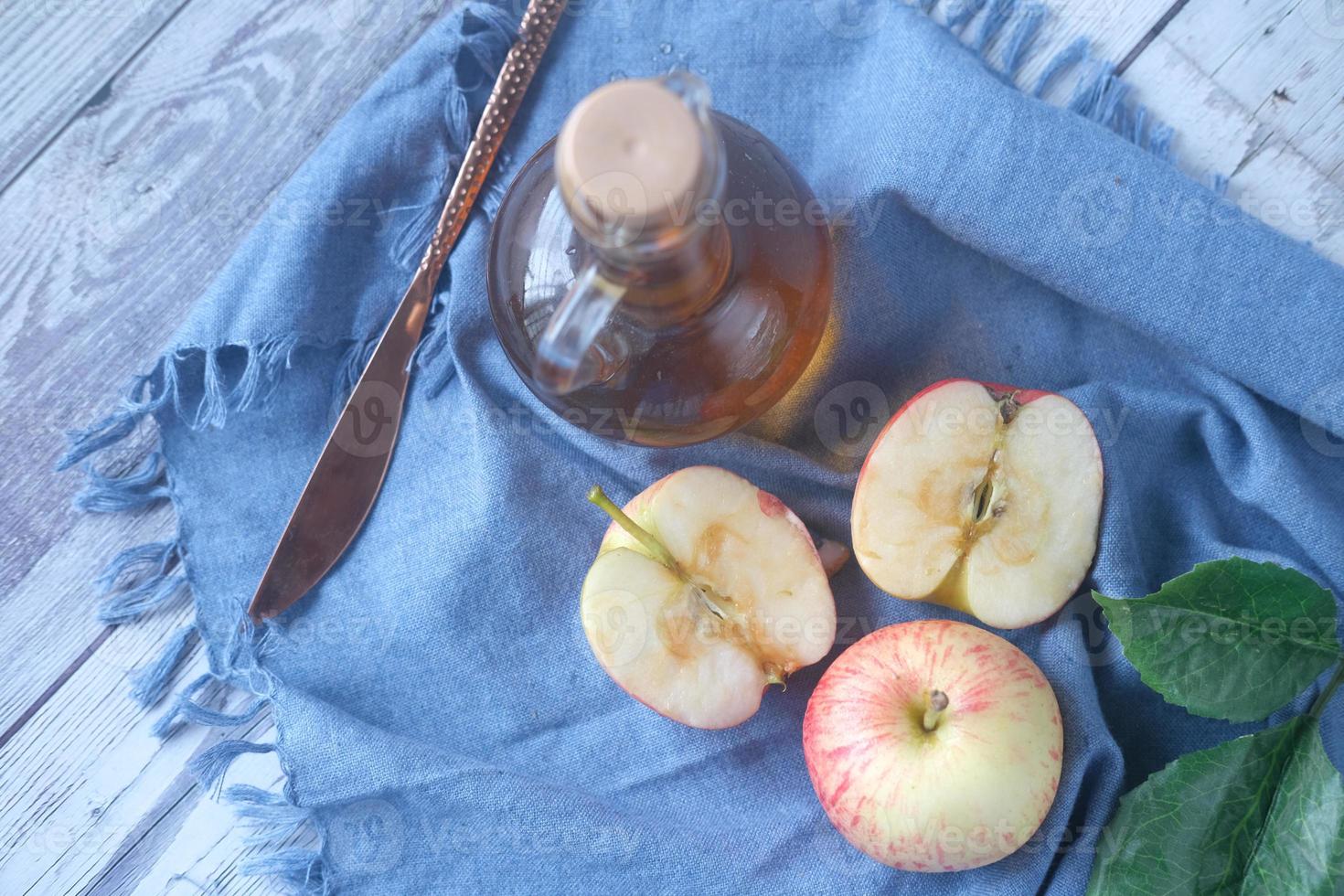 äppelvinäger i glasflaska med färskt grönt äpple på bordet foto