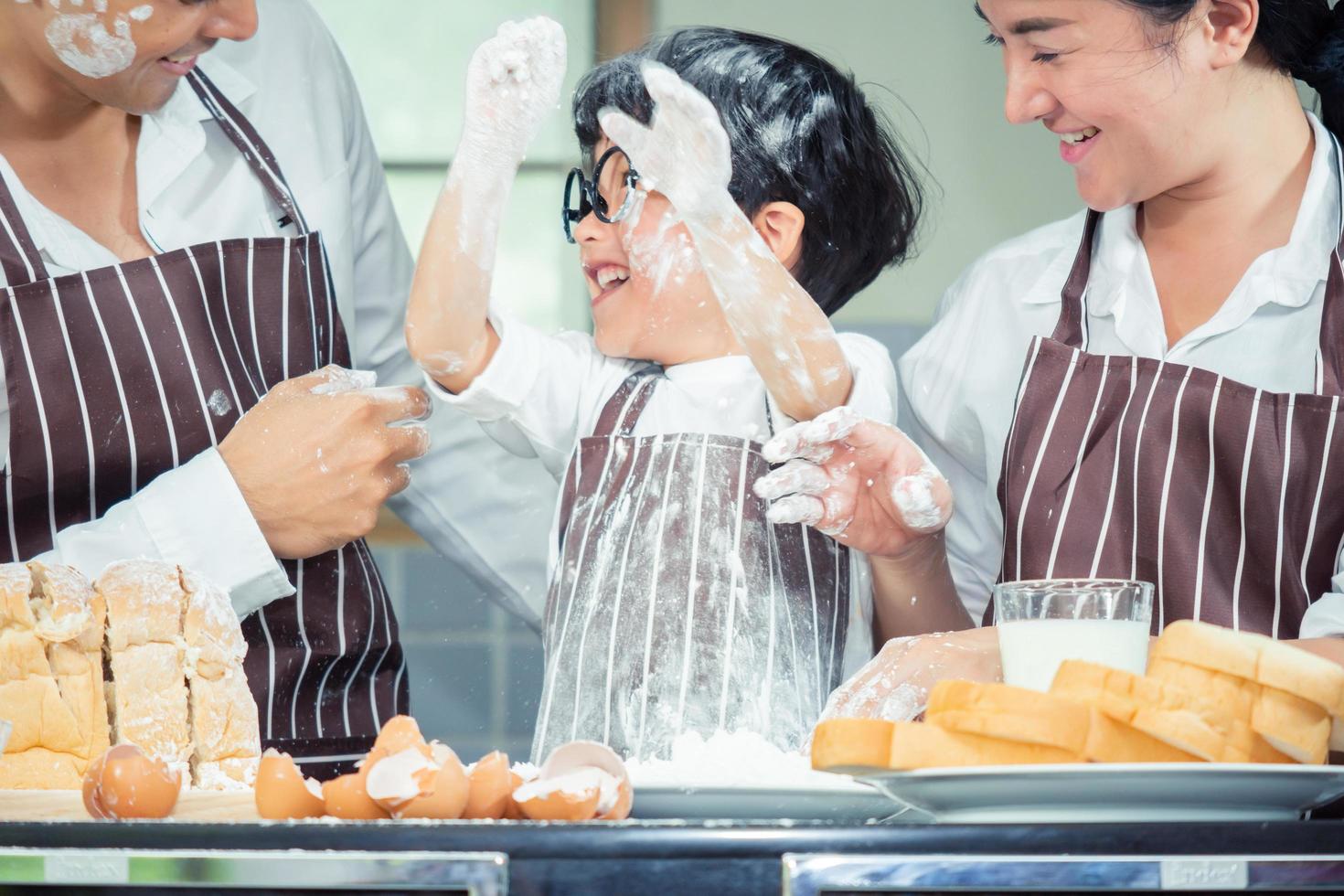 asiatisk pojke bär glasögon retar pappa matlagning foto