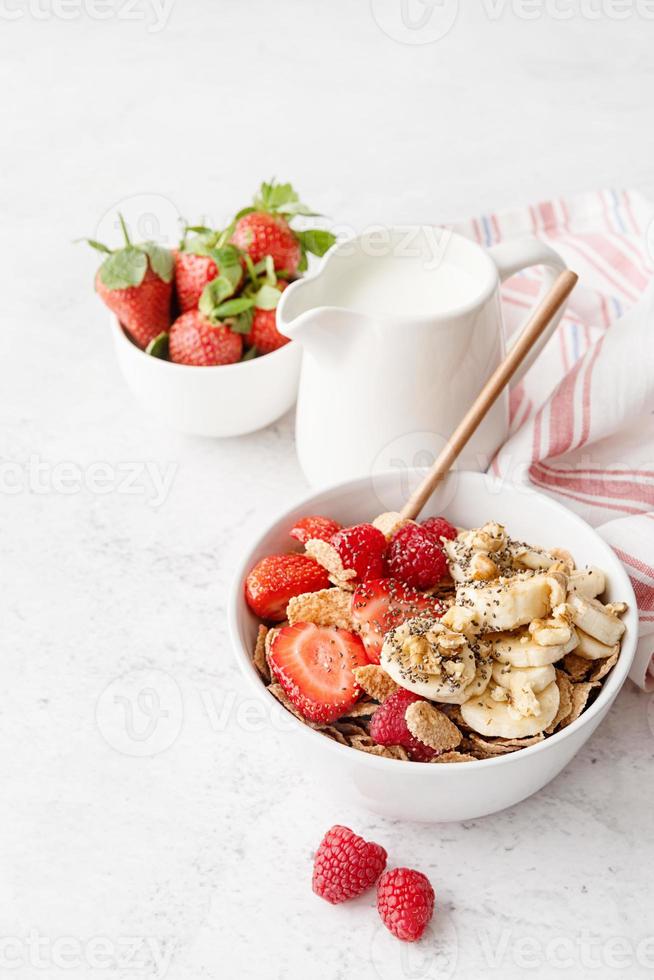 hälsosam frukost, flingor, färska bär och mjölk i en skål foto