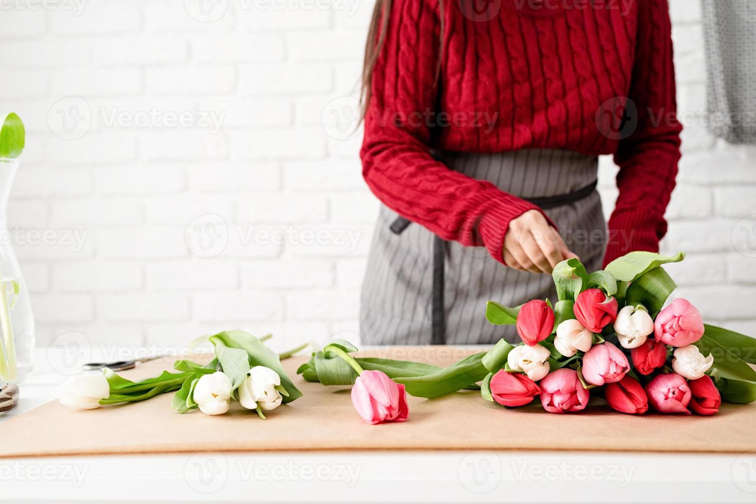 kvinna blomsterhandlare som gör en bukett med färska färgglada tulpaner foto