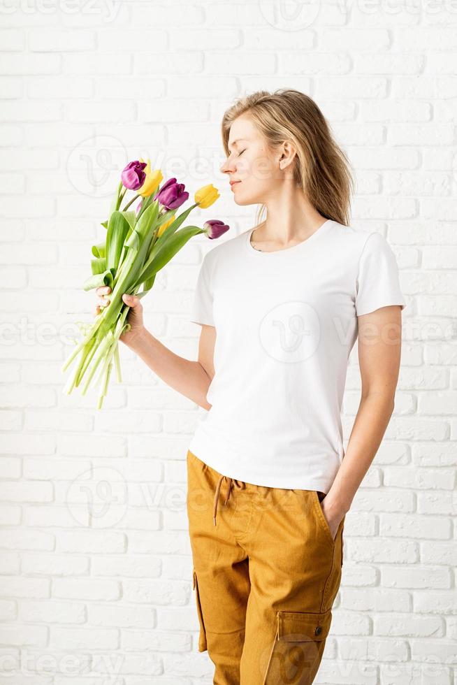 kvinna som bär tomma vita t-shirtinnehav tulpanblommor foto