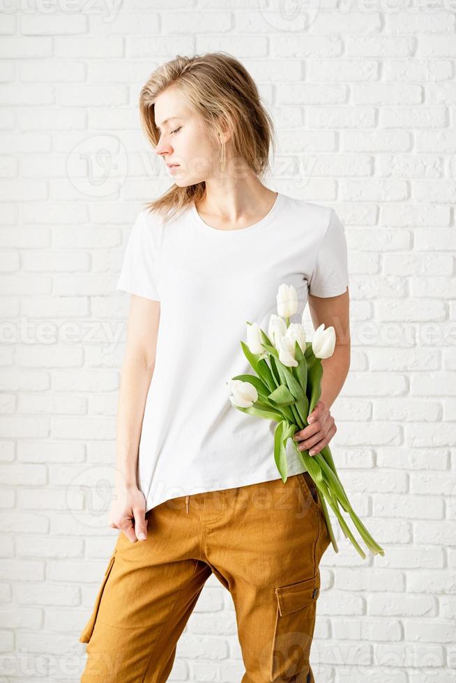 kvinna som bär tomma vita t-shirtinnehav tulpanblommor foto