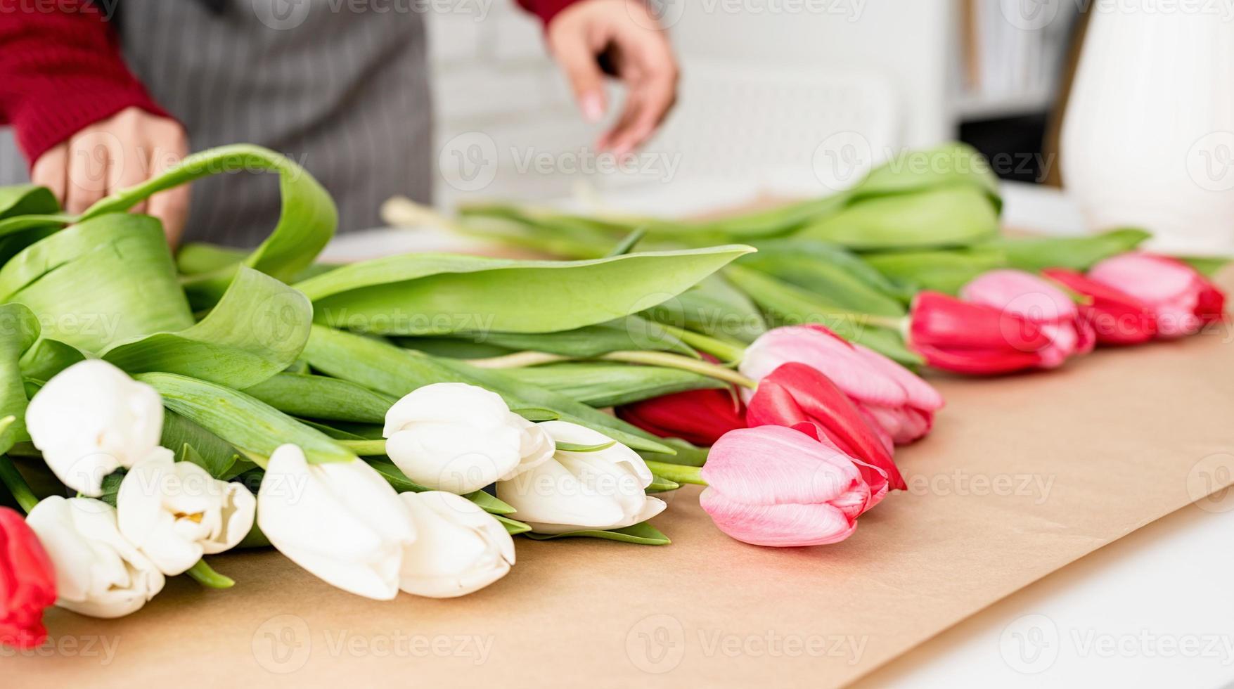 kvinna blomsterhandlare som gör en bukett med färska färgglada tulpaner foto