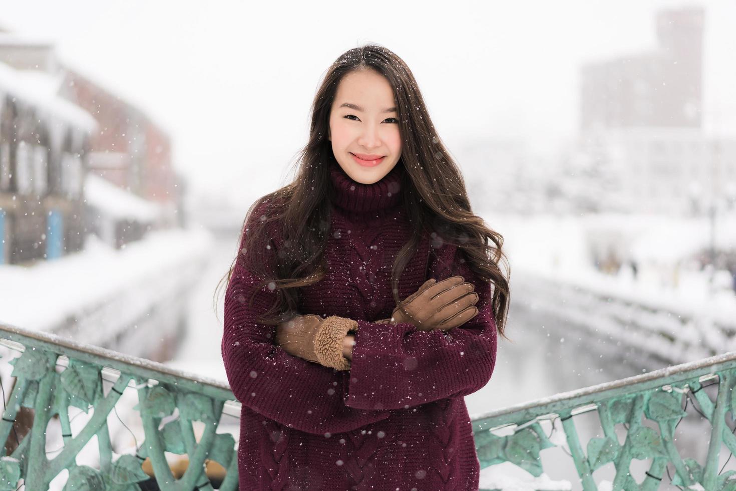 asiatisk kvinna som ler glad för att resa i snö vintersäsongen foto