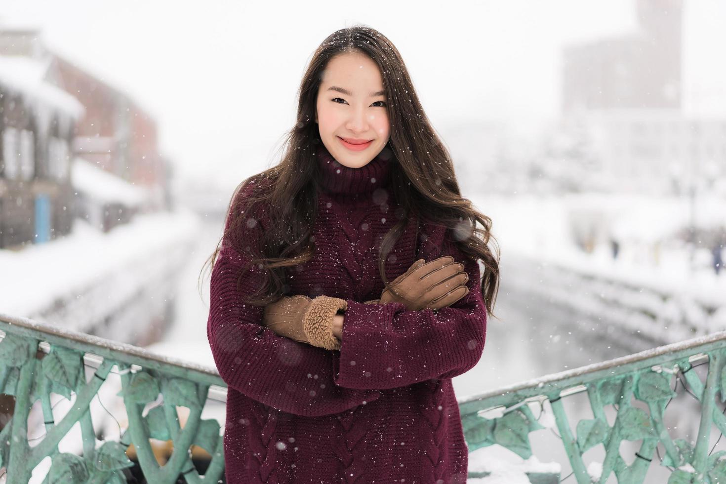 asiatisk kvinna som ler glad för att resa i snö vintersäsongen foto