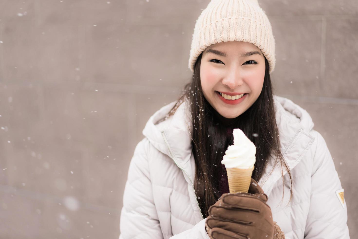 ung asiatisk kvinnaleende och nöjd med glass i snövintersäsongen foto
