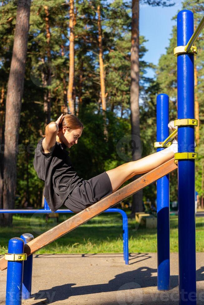 en Tonårs flicka håller på med abdominal crunches. foto