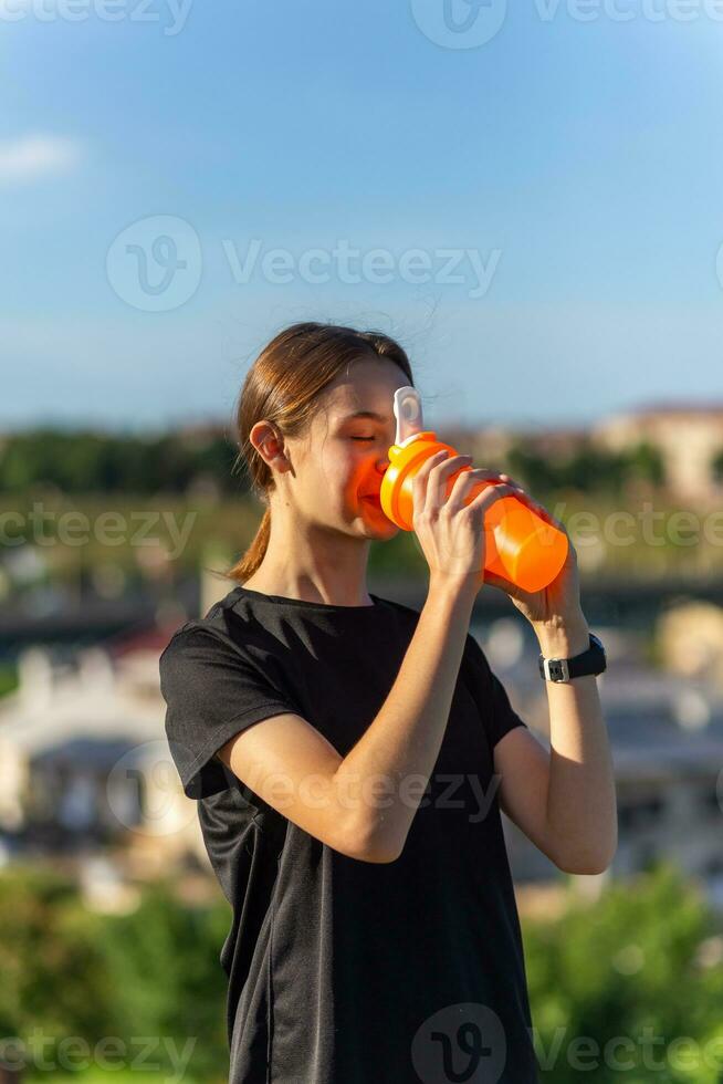 passa tennage flicka löpare utomhus innehav vatten flaska. foto
