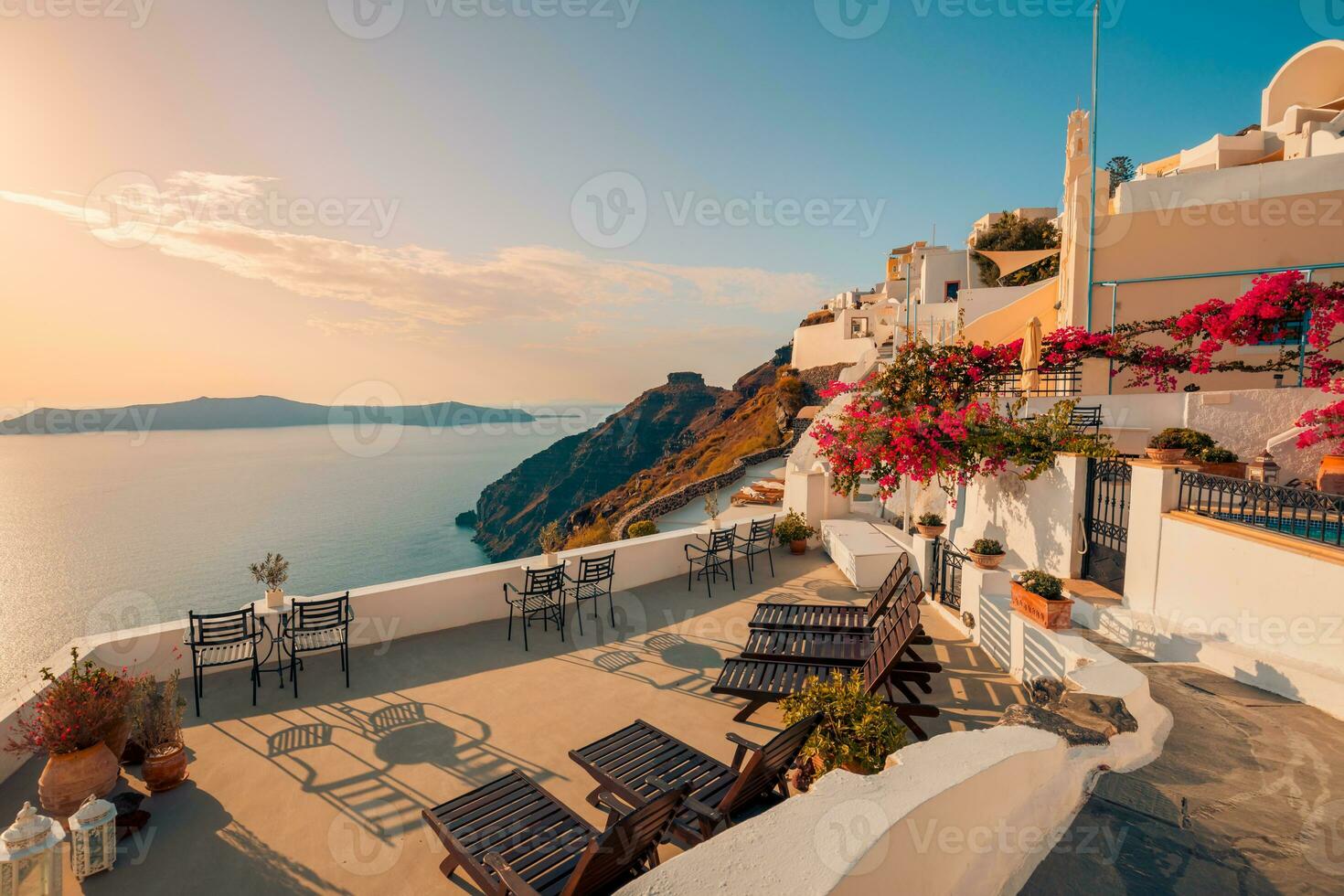 vit arkitektur på ön Santorini, Grekland. utomhusrestaurang under ett fantastiskt solnedgångslandskap, stolar för par. romantisk solnedgång, orange himmel och moln. sommarlov, smekmånadsresor foto