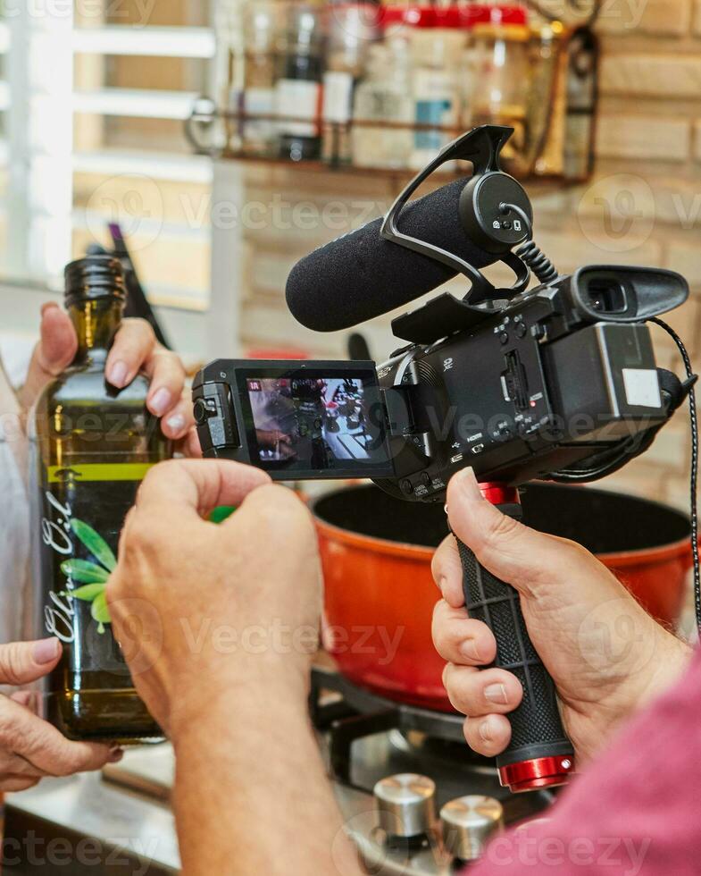 de är filmning video av matlagning, flaska av oliv olja i de händer av de laga mat foto