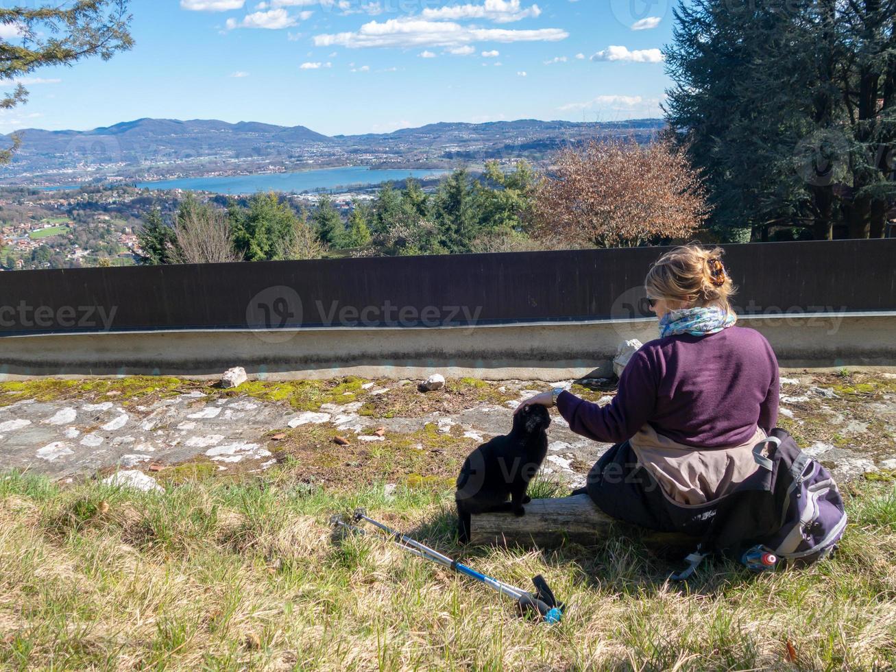 flicka sitter på marken smeka en svart katt i bergen foto