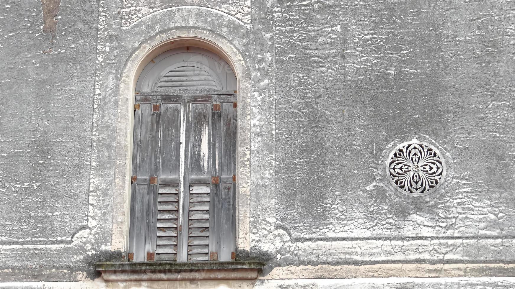 välvt fönster i venetiansk stil och ett litet runt dekorativt fönster foto