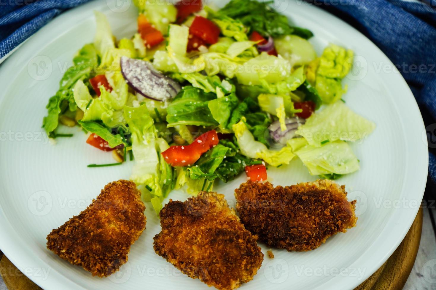 gyllene stekta kycklingklumpar med sallad foto