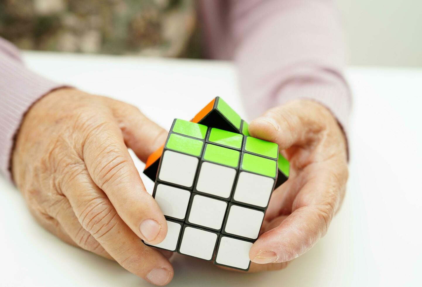 Bangkok, thailand - Maj 15, 2022 asiatisk äldre kvinna spelar rubik kub spel till öva hjärna Träning för hjälp demens förebyggande och alzheimers sjukdom. foto