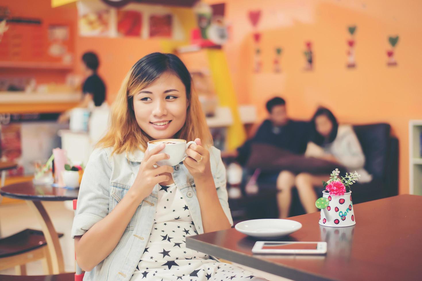 ung vacker kvinna som sitter på ett kafé som håller varmt kaffe. foto