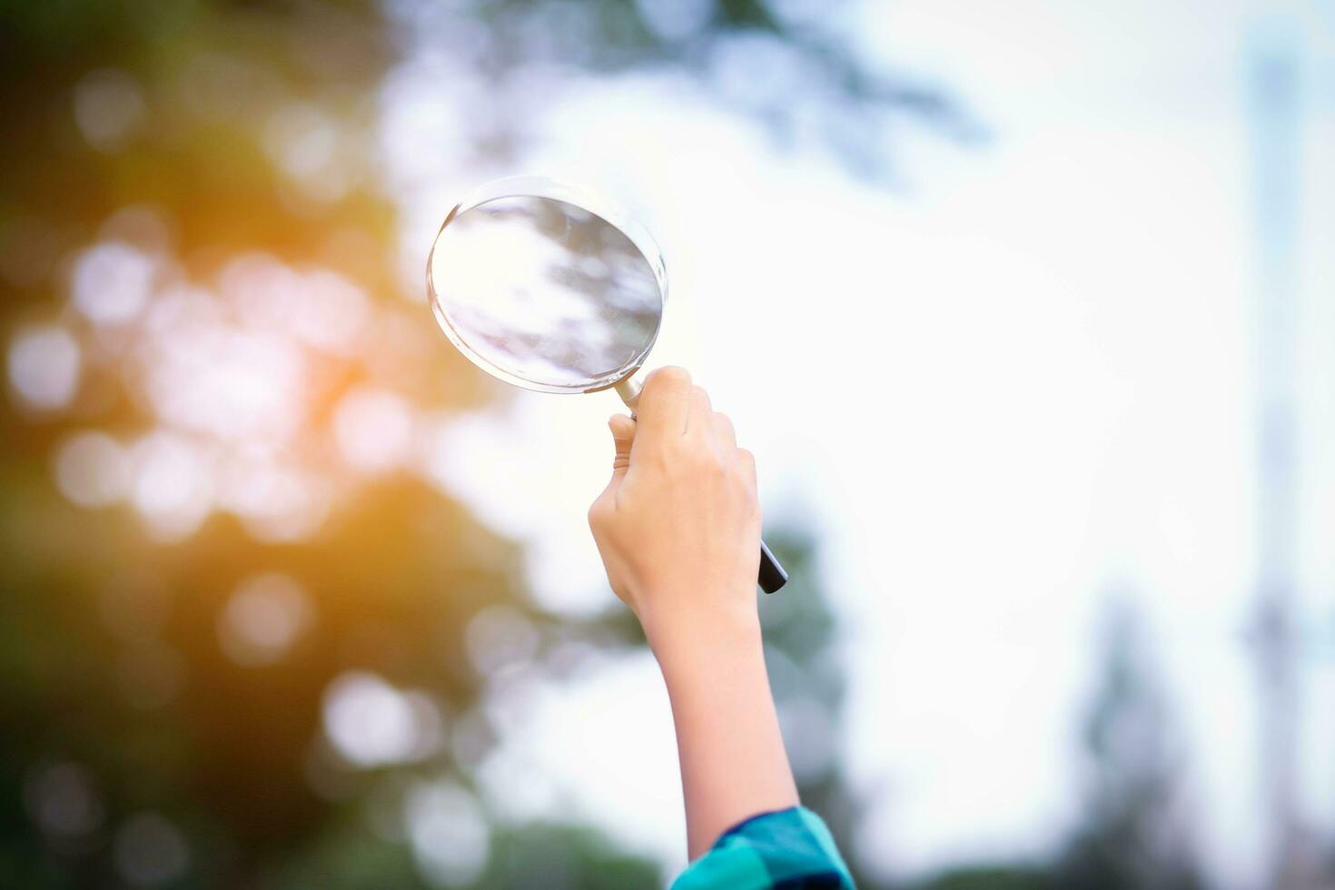 asiatisk liten flicka är använder sig av förstorande glas till spela i de park.sstkhome foto