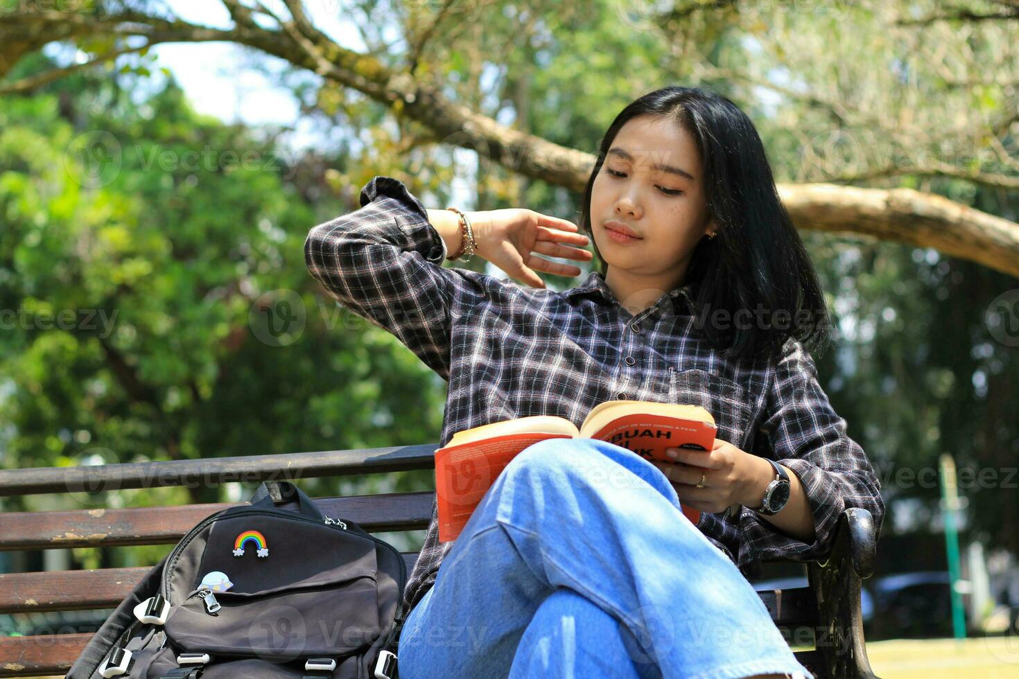 Lycklig uppmärksam ung asiatisk kvinna högskola studerande läsning en bok i de parkera, utbildning begrepp foto