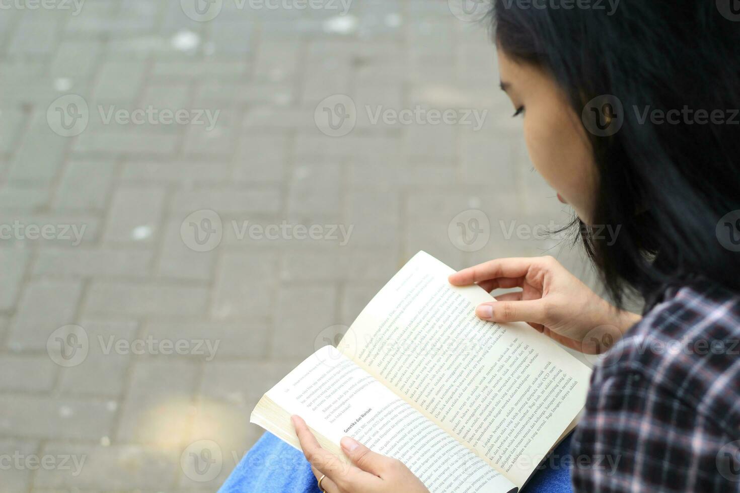 Lycklig och succes kvinna asiatisk högskola studerande njuter läsa en bok i de parkera foto