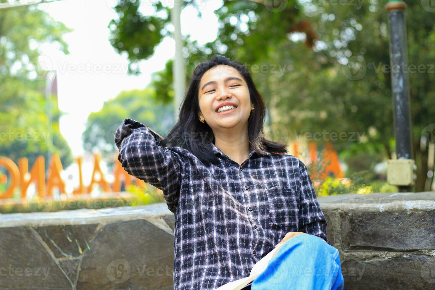 Lycklig glad asiatisk kvinna studerande läsning en bok och skrattande njuter semester foto