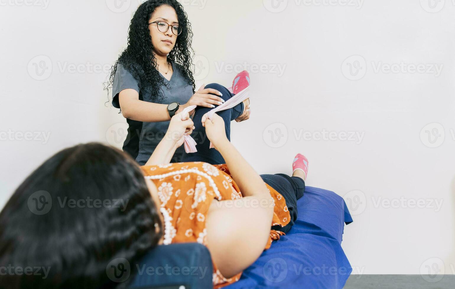 kinesiolog med patient knä med motstånd band, knä rehabilitering fysioterapi med motstånd band. fysioterapeut kvinna rehabilitering knä till patient med motstånd band foto