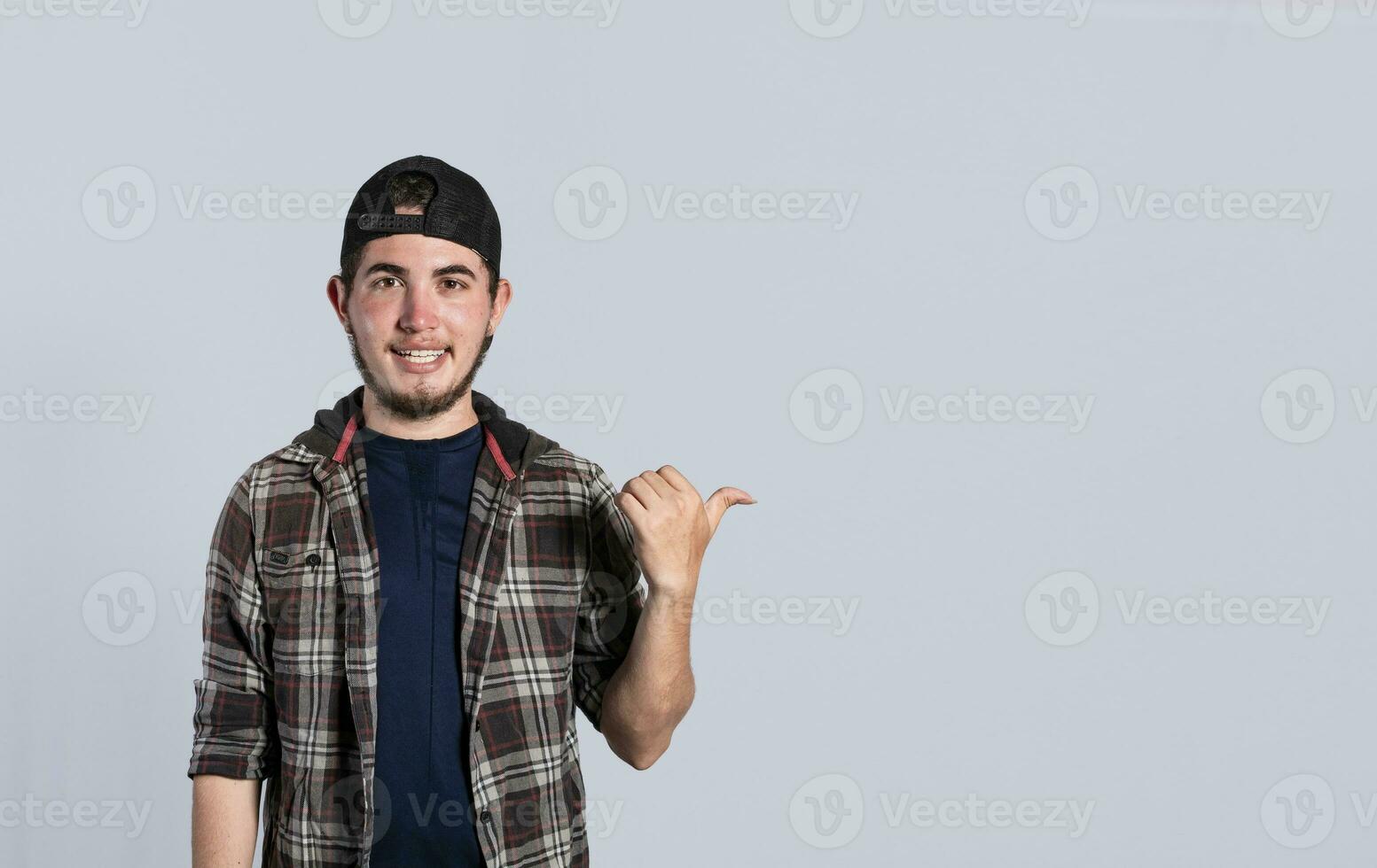 glad skäggig man med en vänlig leende visar du de riktning till en trevlig plats, en vänlig kille pekande hans tumme till hans rätt foto