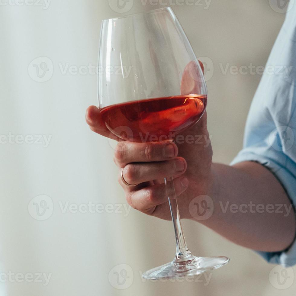en man håller ett glas rött vin i sin högra hand foto