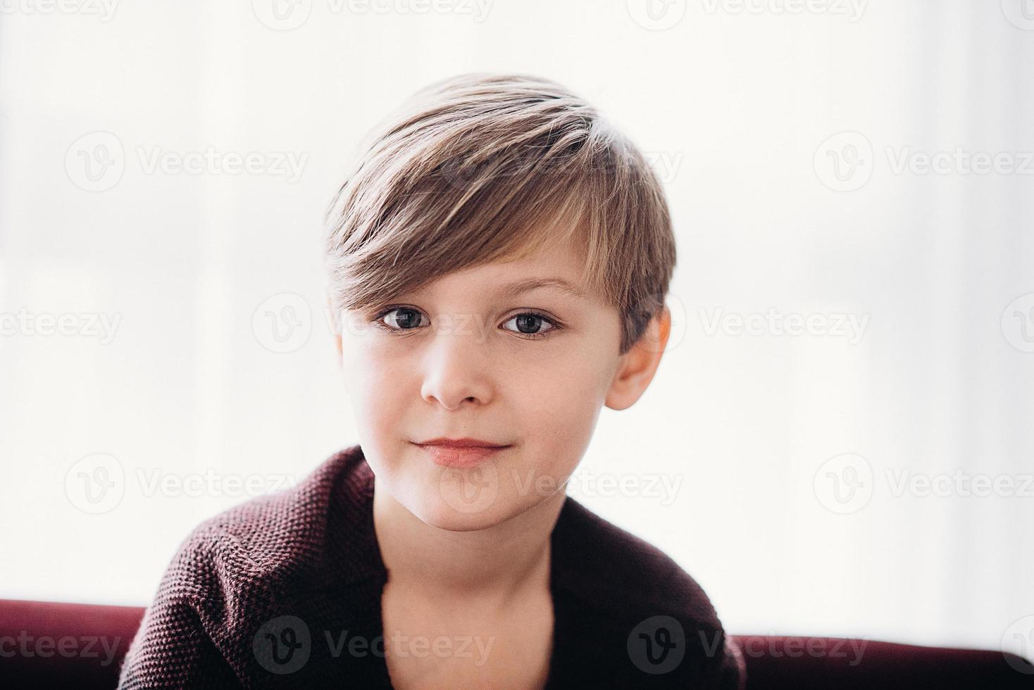 en söt pojke som sitter mot fönstret, mjukt fokus foto