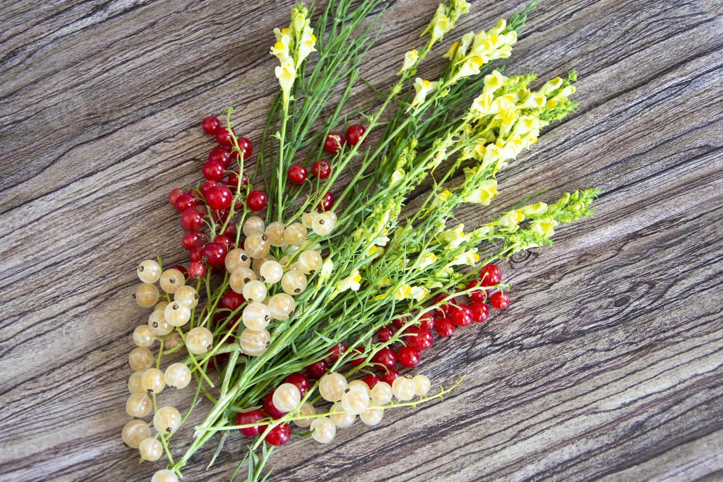 bukett vildblommor med vinbärbär på en träbakgrund foto