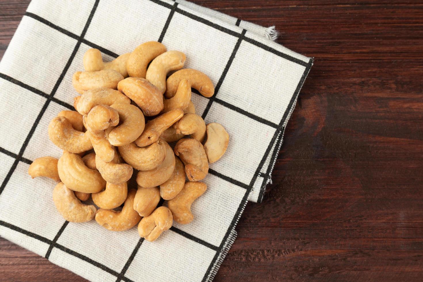 cashewnötter i bordsduk på träbord, hälsosamt mellanmål foto