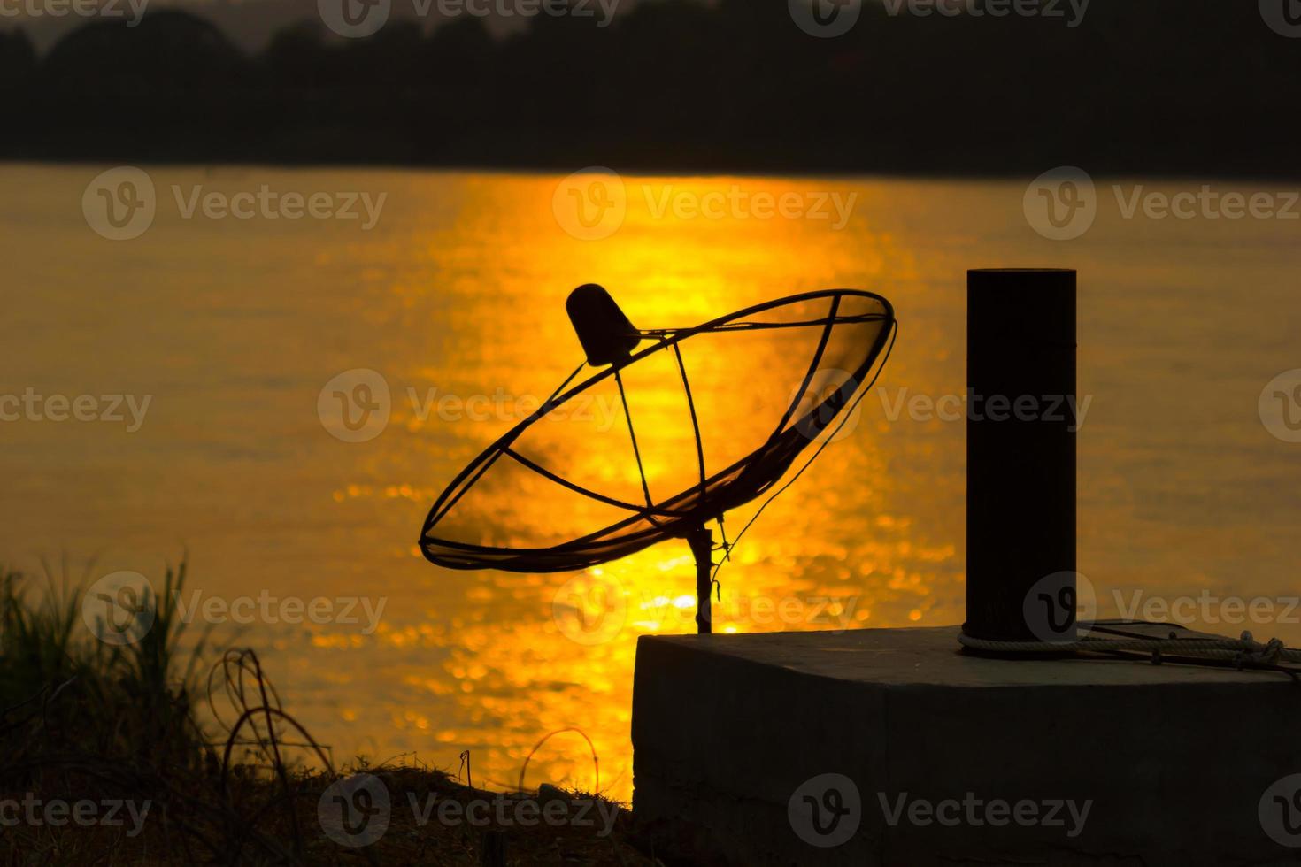 parabolantenn på reflektionen över floden i solnedgången bakgrund foto