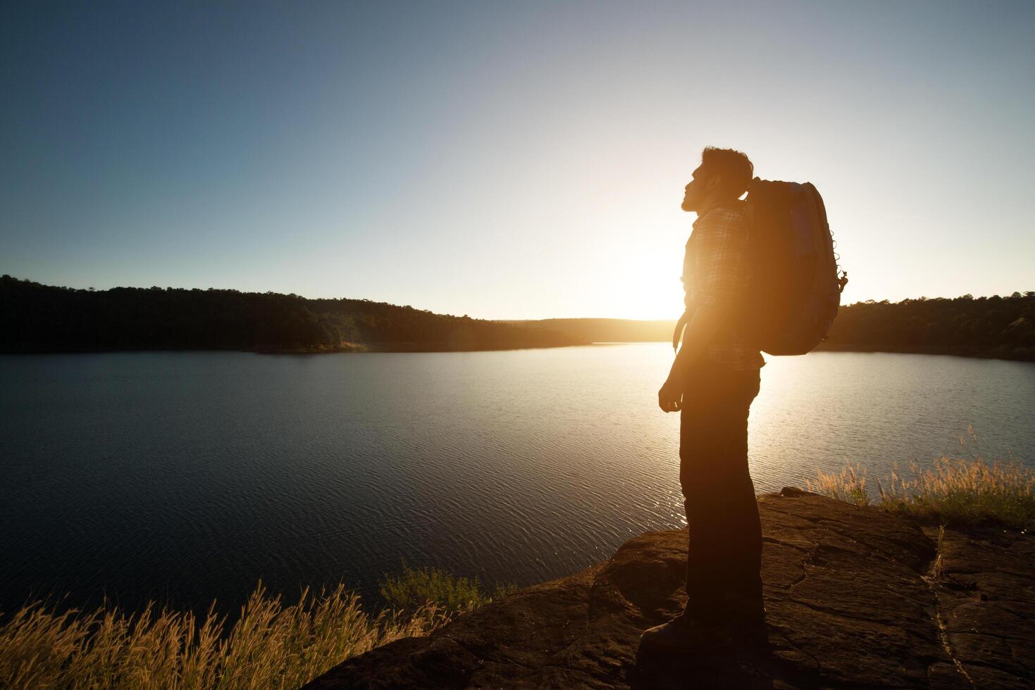 silhuett av vandrare mannen med ryggsäck i solnedgången landskap berg. foto