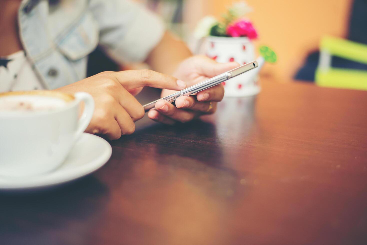 närbild av kvinnahänder sms med sin mobil på kaféet. foto