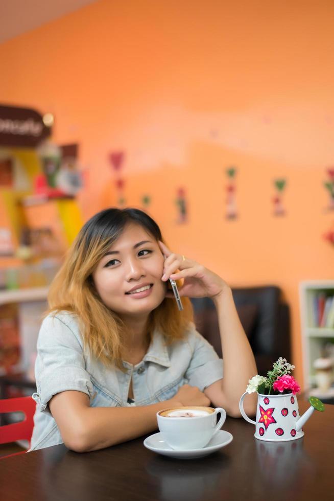 ung vacker kvinna prata telefon på kafé ser så glad. foto