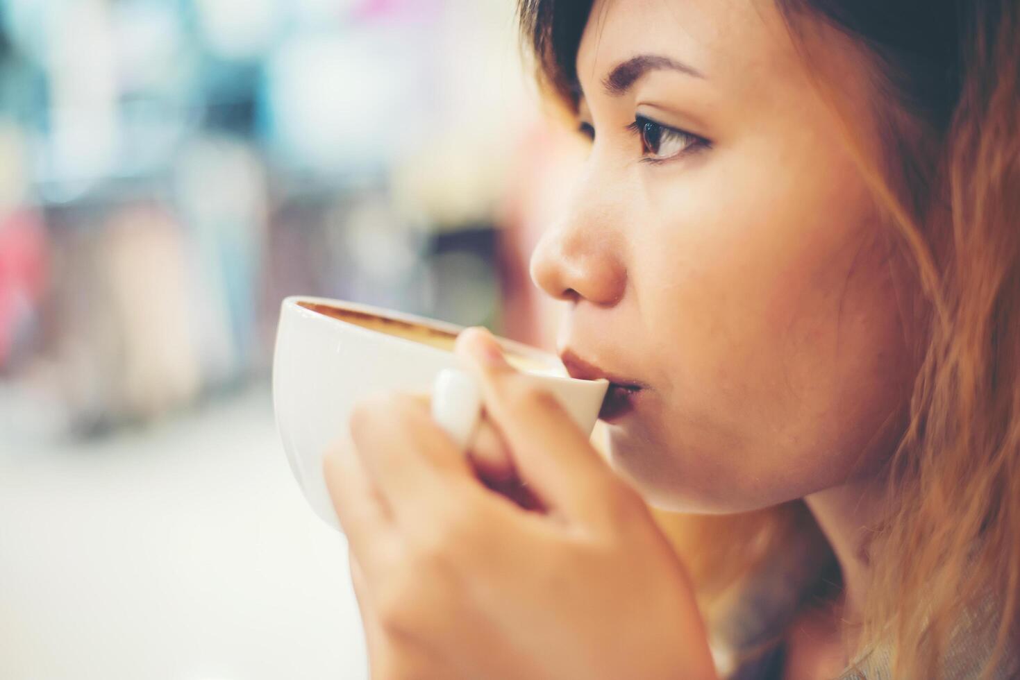 ung vacker kvinna dricka varmt cappuccino kaffe på café. foto