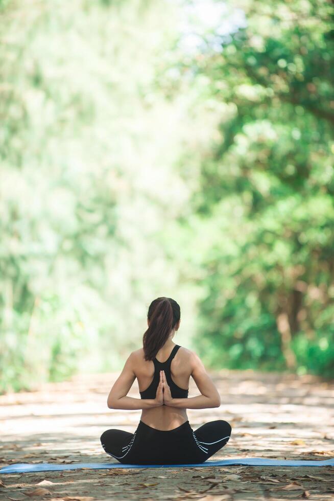 ung asiatisk kvinna som gör yoga på morgonen i parken. hälsosam foto