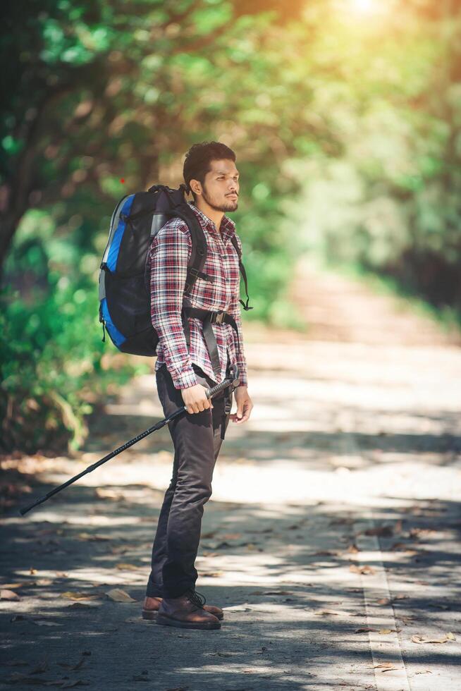 hipster man vandrare håller stolpar och tittar bort. foto