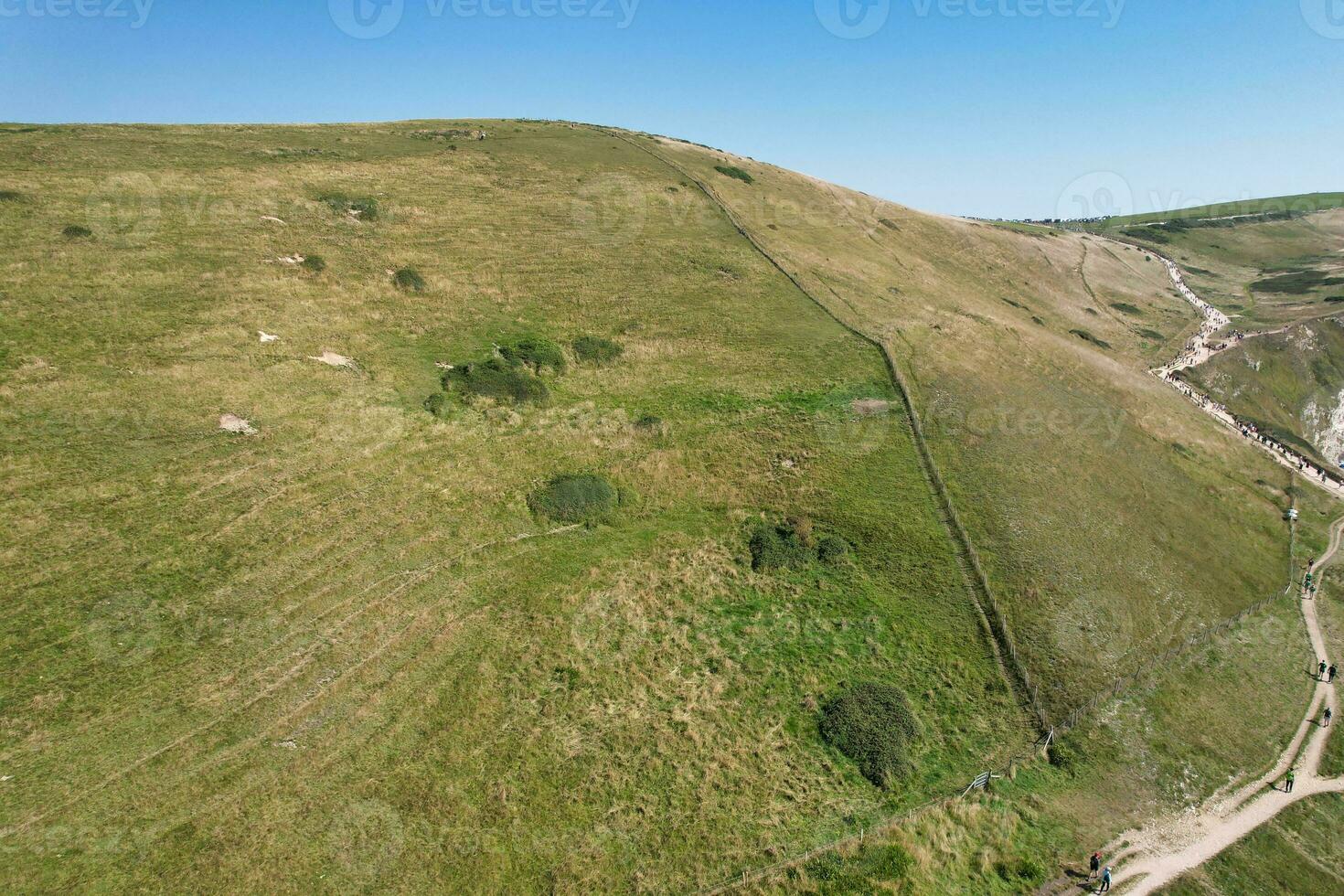 hög vinkel se av människor är närmar sig till durdle dörr strand som är mest känd turist attraktion plats genom gående distans över landskap och kullar. fångad på september 9:e, 2023 foto