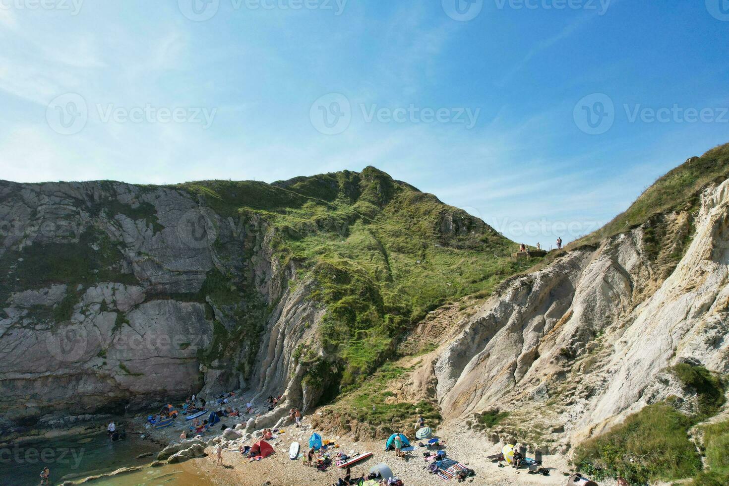 hög vinkel se av människor är närmar sig till durdle dörr strand som är mest känd turist attraktion plats genom gående distans över landskap och kullar. fångad på september 9:e, 2023 foto