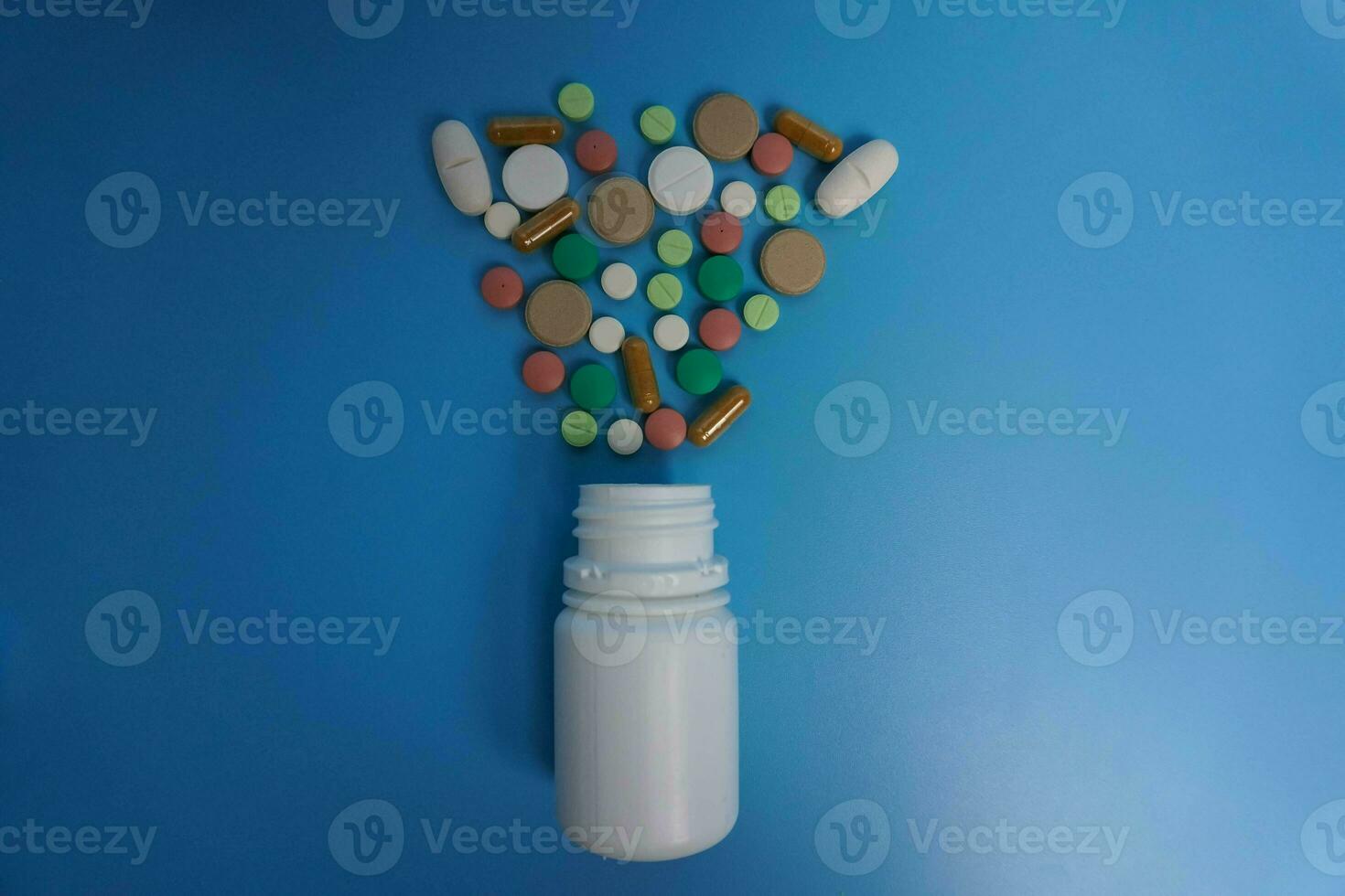 topp se blandad färgrik farmaceutisk medicin biljard, tabletter och kapslar och vit flaskor på blå bakgrund. kopia Plats för text foto