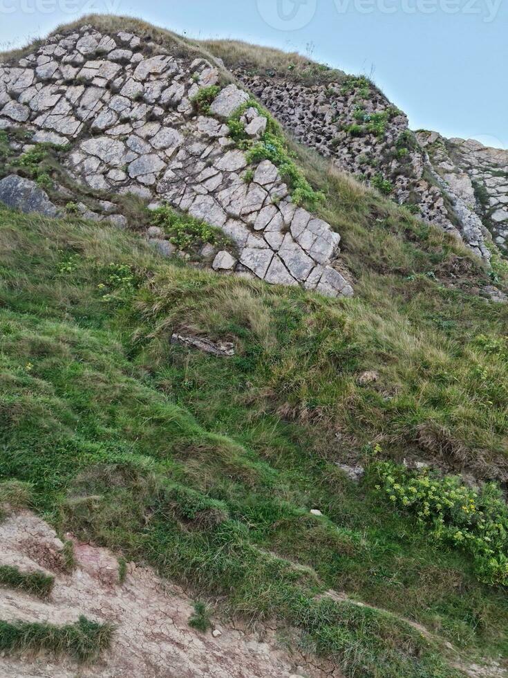 hög vinkel se av människor är närmar sig till durdle dörr strand som är mest känd turist attraktion plats genom gående distans över landskap och kullar. fångad på september 9:e, 2023 foto