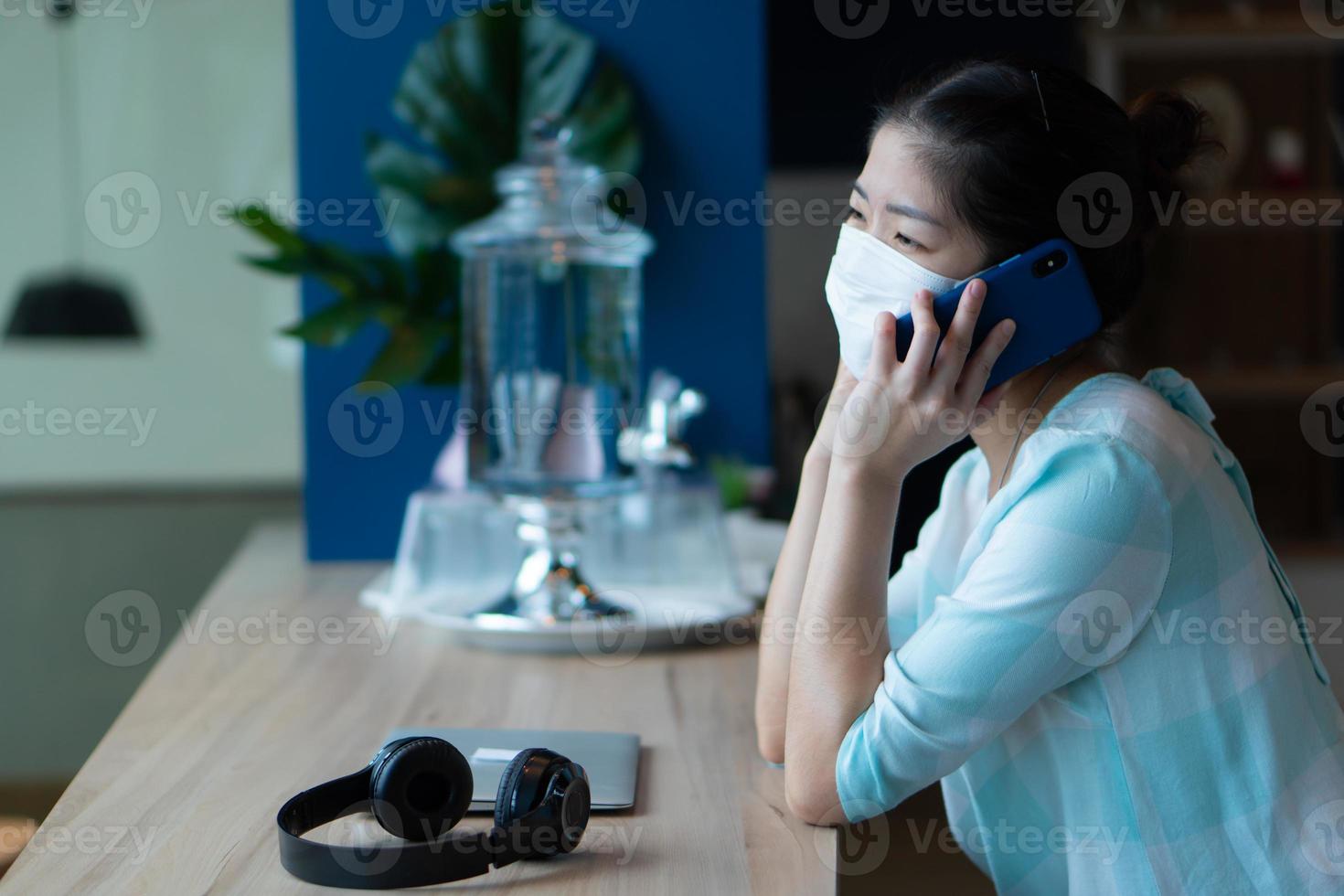 asiatisk kvinna med mask och hålla social distans på café foto